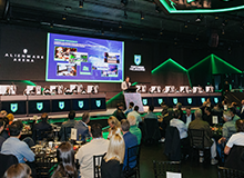 A large group of people sitting at tables in the Alienware Arena