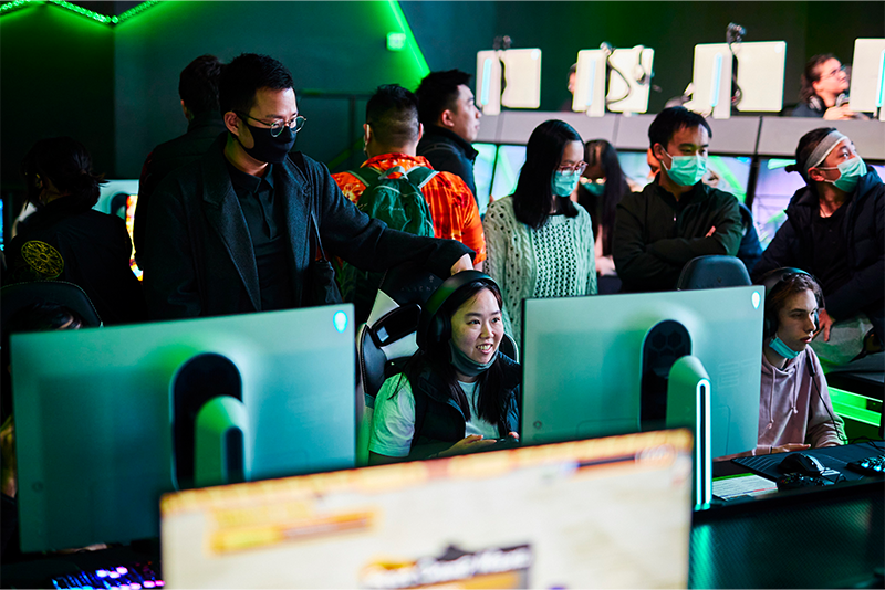 A group of people around PC's playing games and smiling in the Alienware Arena